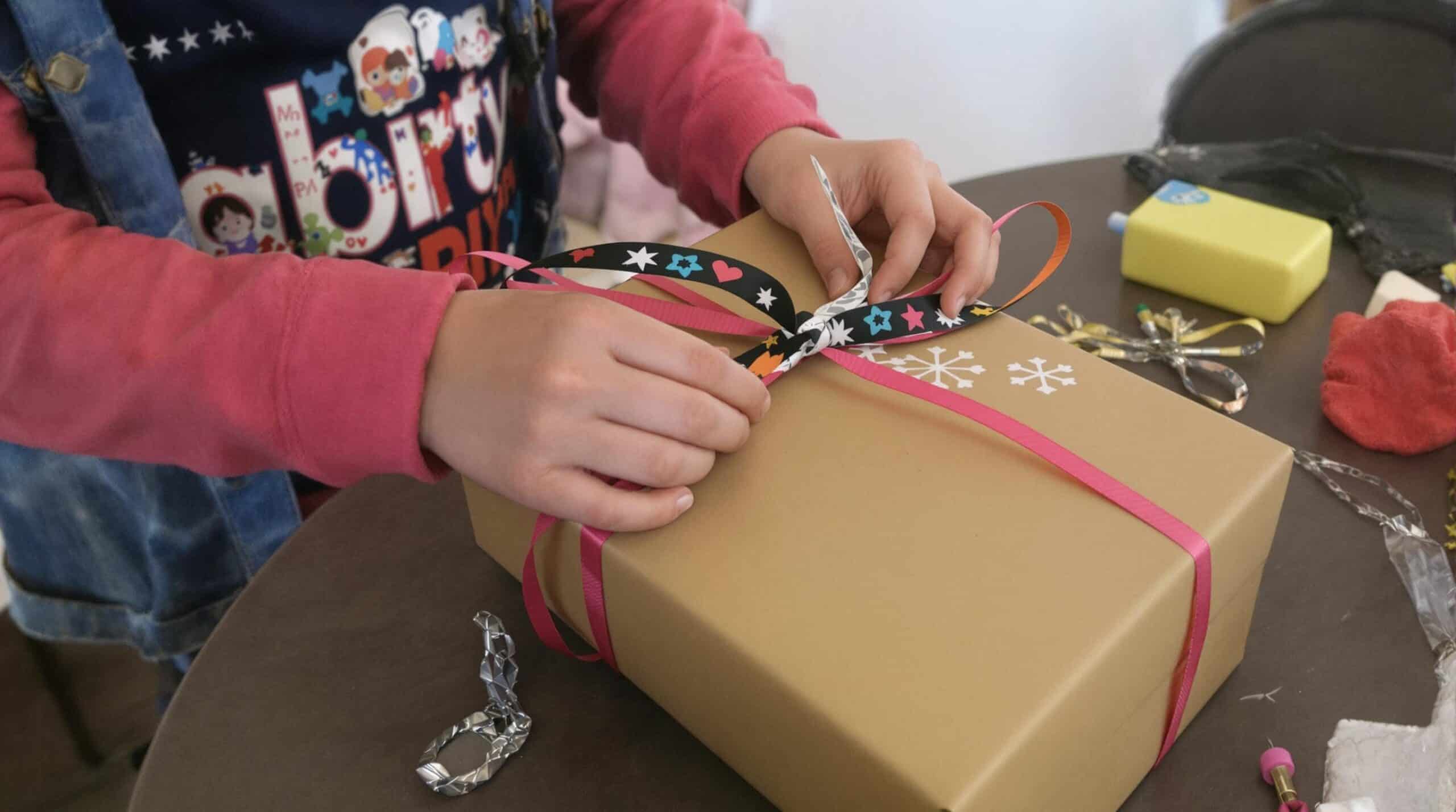 Un enfant emballe un cadeau qu'il a fait lui-même