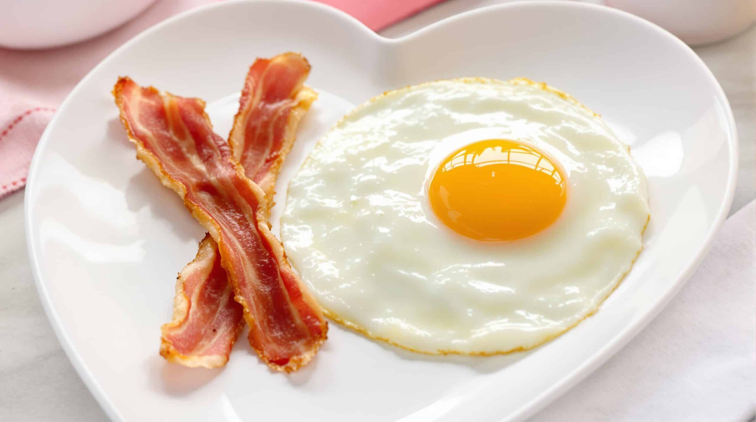 Œufs et bacon sur une assiette en forme de cœur