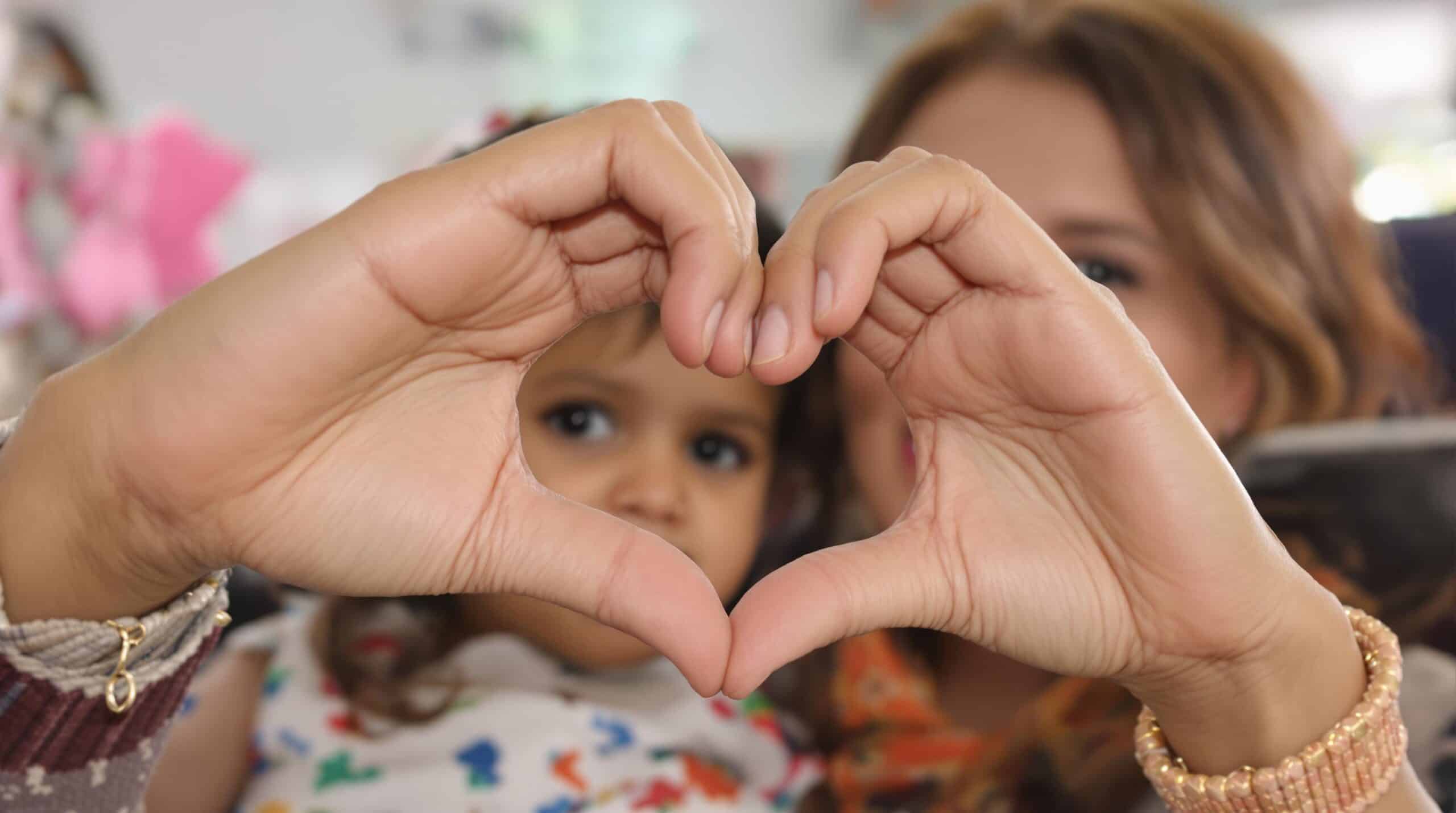 Une femme et sa fille forment un cœur avec leurs mains