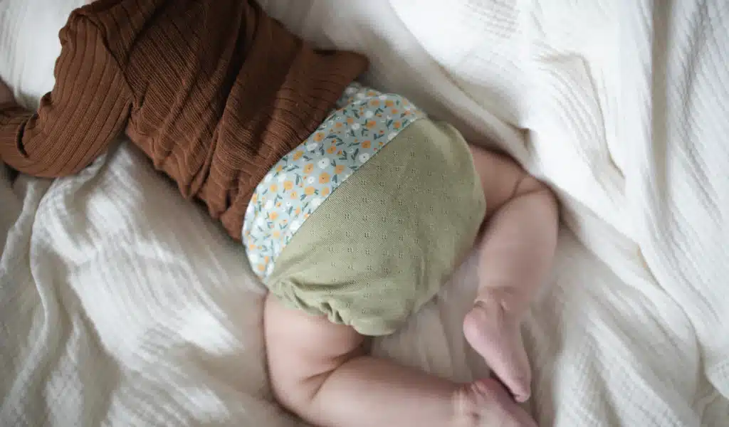 Le corps d'un bébé photographié de dos avec une couche en tissu dessus.