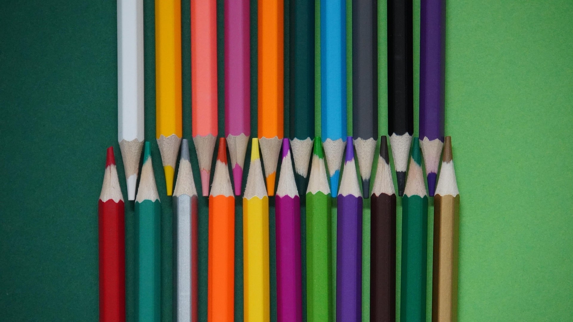Des crayons de différentes couleurs sont posés sur un fond uni.